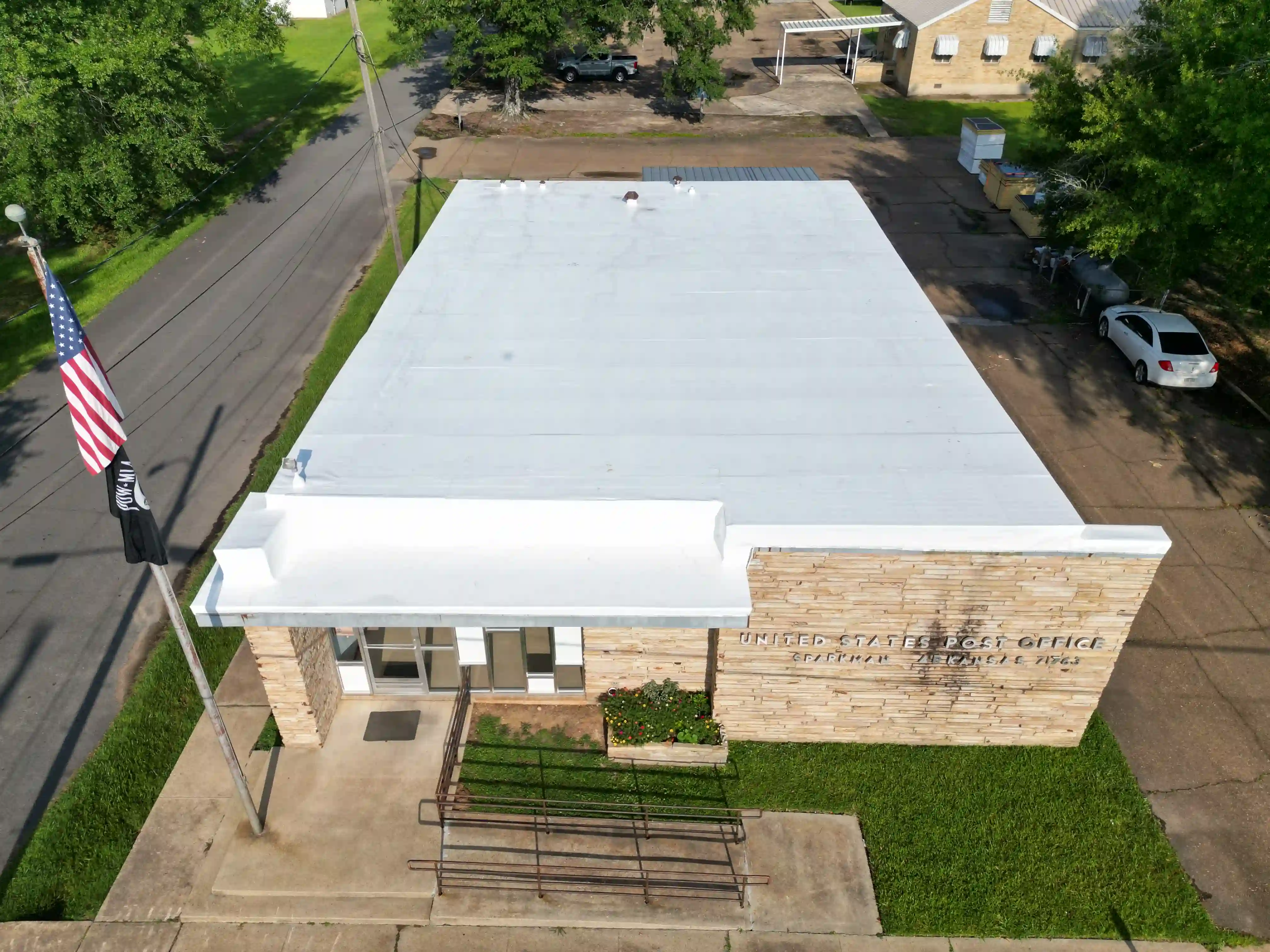 Low-slope white membrane roof with drains and rooftop units on a retail-scale building